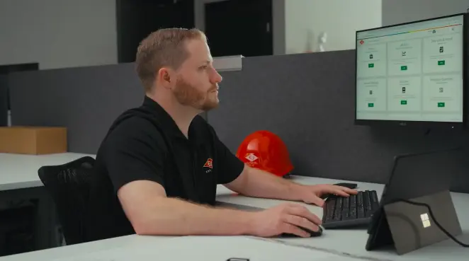 Construction professional reviewing Riskcast software at desk with hard hat