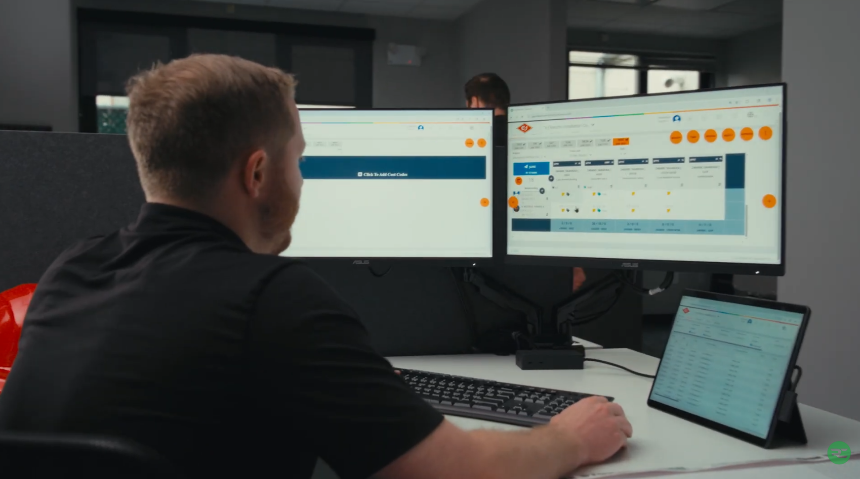 Construction professional reviewing Riskcast forecasting dashboard on dual monitors